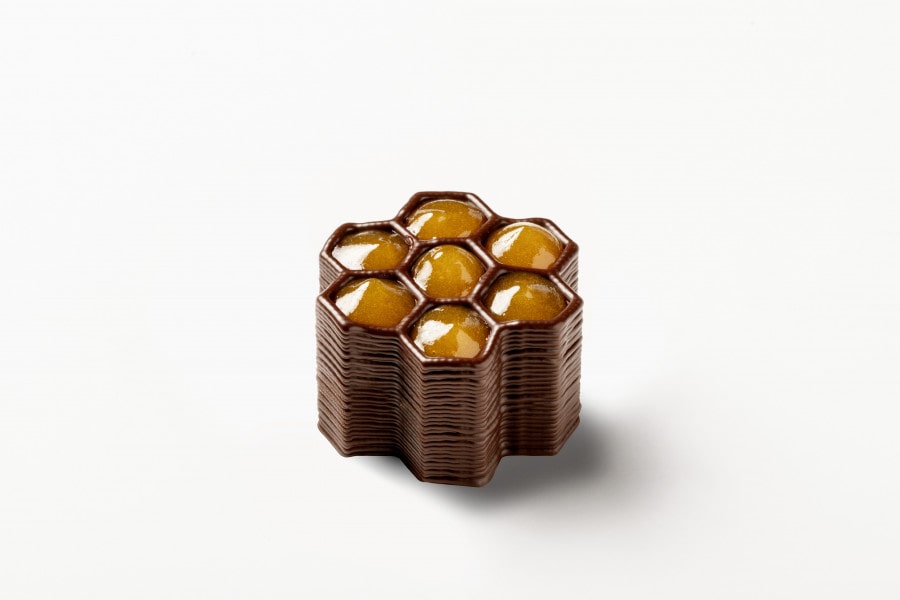 FoodJet社が制作したチョコレート。蜂の巣の様なハニカム構造のチョコレートの壁と、その穴の中に金色のシロップが充填されている。